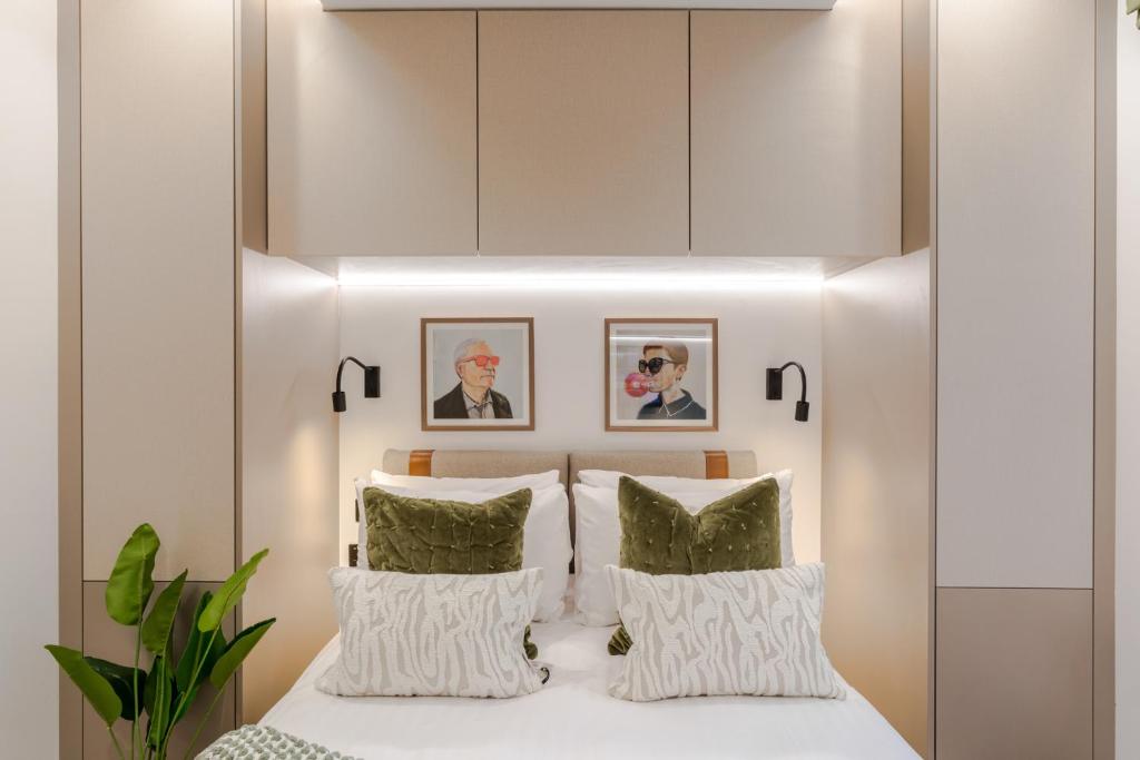 a bedroom with a white bed with green pillows at Kensington I Your Apartment in London