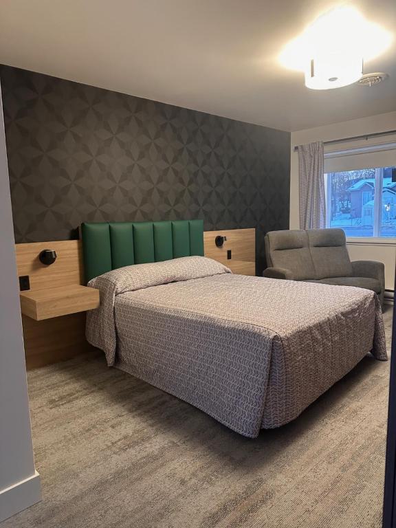 a bedroom with a large bed and a chair at Motel Blanche d'Haberville in Saint-Jean-Port-Joli