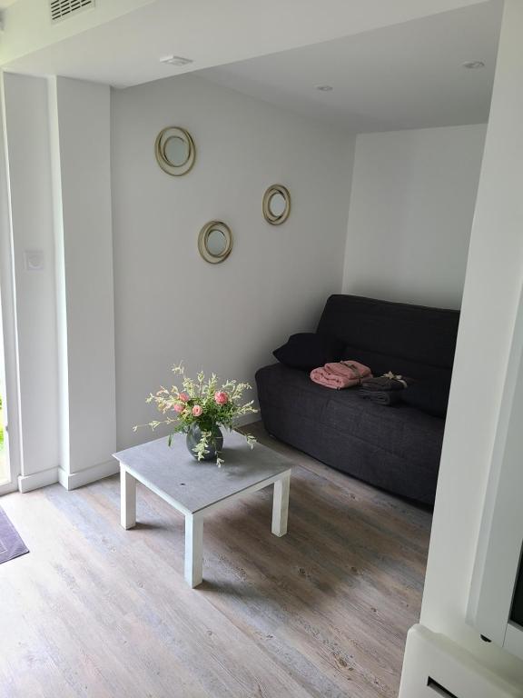 un soggiorno con un divano e un tavolo con fiori di Studio indépendant a Saint-Égrève