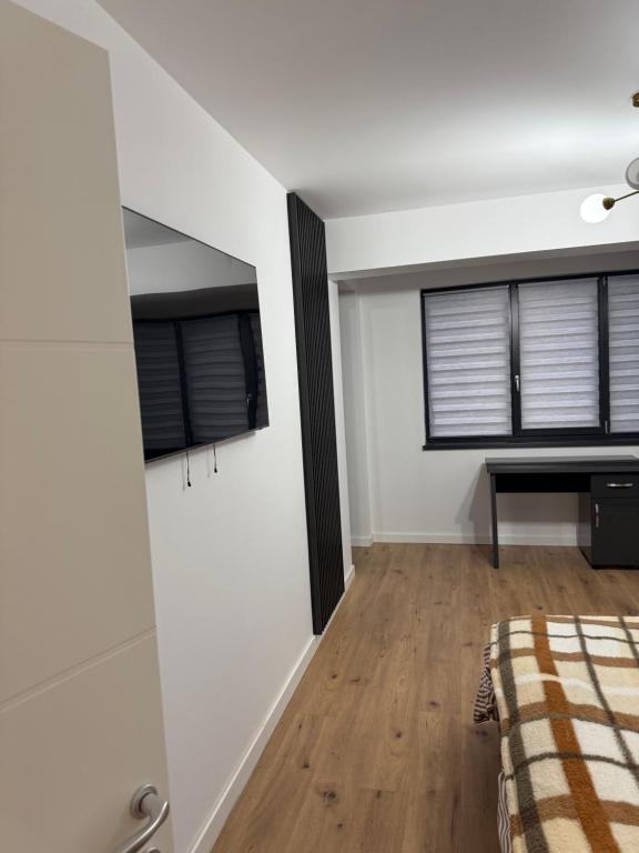a bedroom with white walls and a bed and a desk at Garsonieră Park Residence Vâlcea in Râmnicu Vâlcea