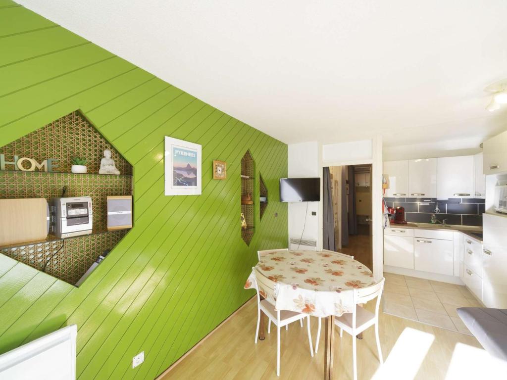 - une cuisine avec une table et un mur vert dans l'établissement Spacieux appart 6 pers avec loggia à Gourette - FR-1-400-127, à Eaux-Bonnes