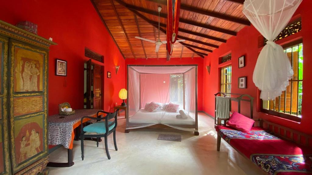 a red room with a bed and a table and chairs at Dragon-Fly Home Hikka in Dodanduwa