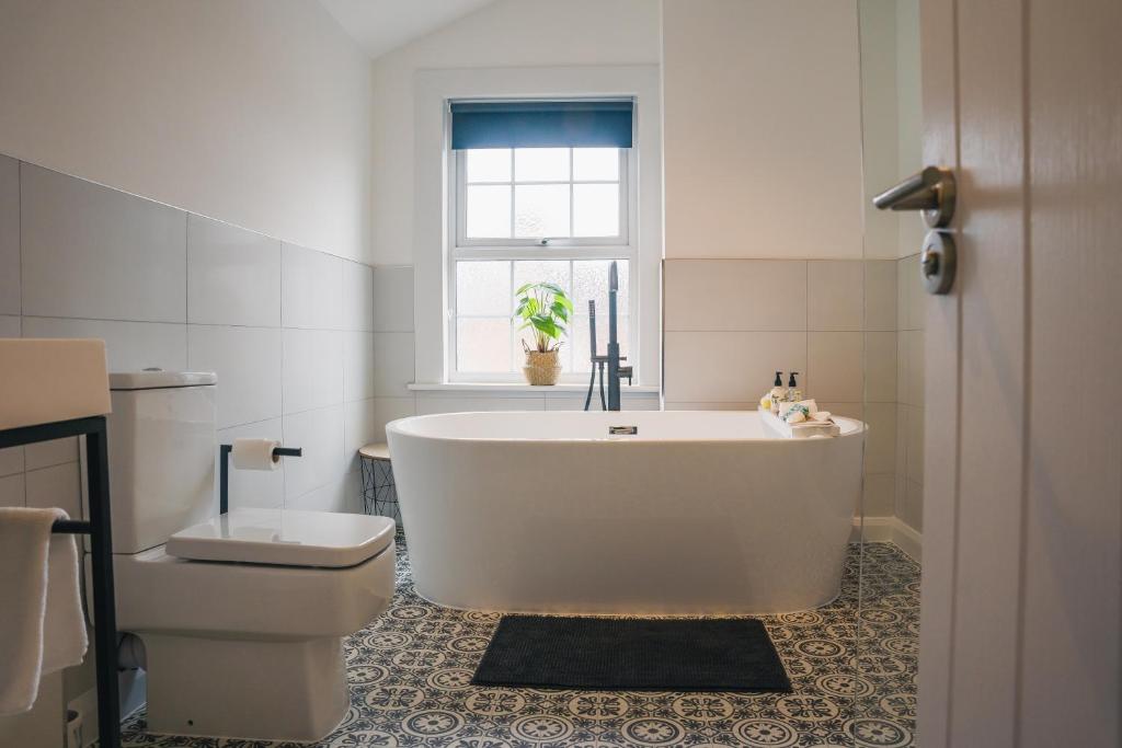 a bathroom with a tub and a toilet and a window at Charming 2-Bedroom home in Leamington Spa in Leamington Spa