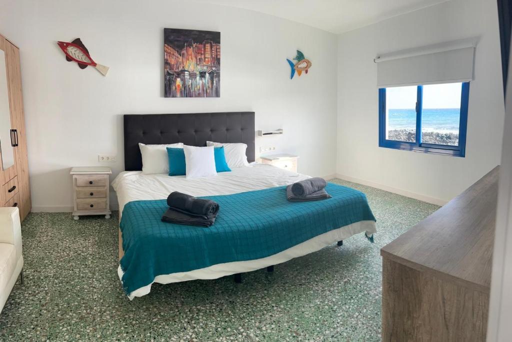 a bedroom with a large bed with a blue blanket at Casa maría in Costa Teguise