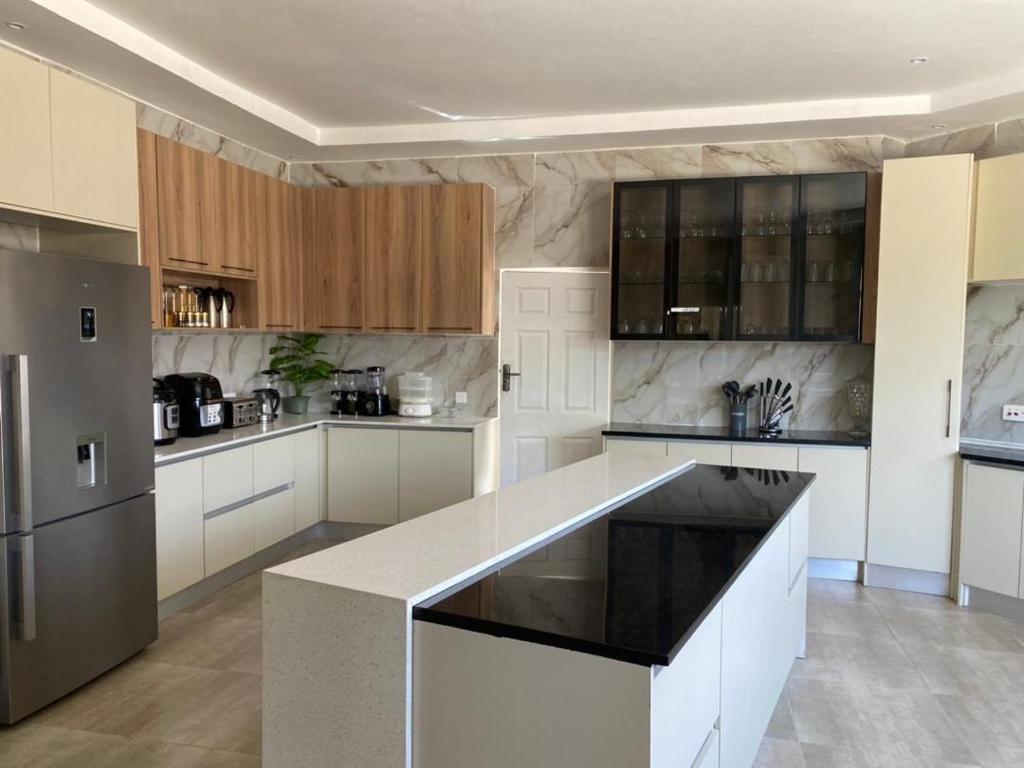 The Residence Hills BnB في هراري: مطبخ بخزائن بيضاء وطاولة عمل سوداء