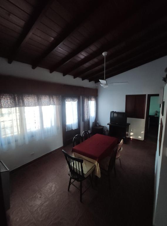 a living room with a table and chairs and windows at Casa Gesell in Villa Gesell