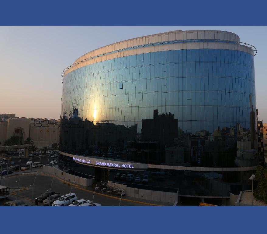 a large glass building with the reflection of a city at Grand Mayral Hotel in Al Khobar