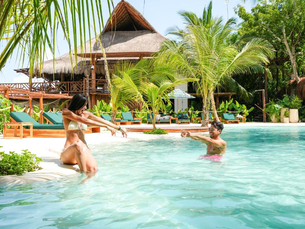 una mujer y dos niños jugando en la piscina de un complejo en Aura Hotel Barú, en Barú