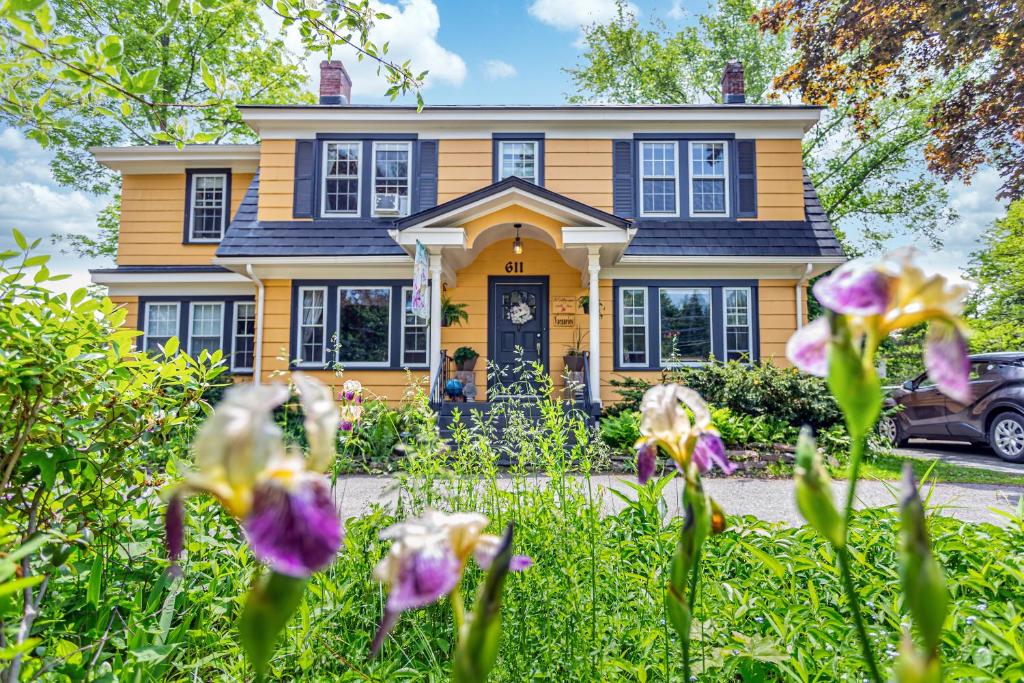 a yellow house with purple flowers in front of it at The Stella Rose B&amp;B in Wolfville