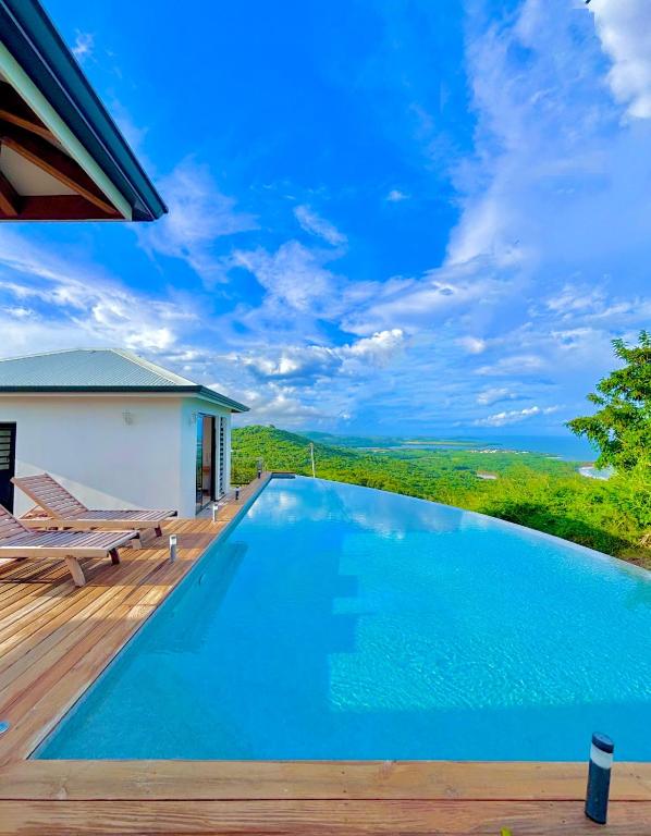a swimming pool on a wooden deck with a view at Villa Vincent des Caps in Le Marin