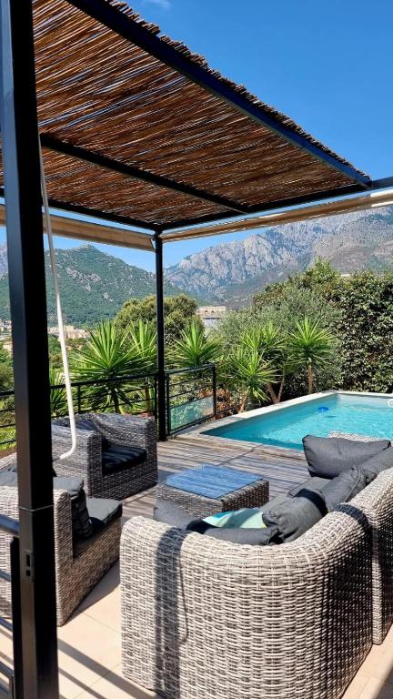 une terrasse avec mobilier en osier et une piscine dans l'établissement Maison moderne avec piscine centre Corse, à Corte