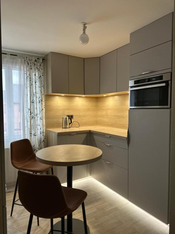 eine Küche mit Tisch und Stühlen und einem Kühlschrank in der Unterkunft Chambre privée "Graine de Coton" - Cuisine partagée in Amiens