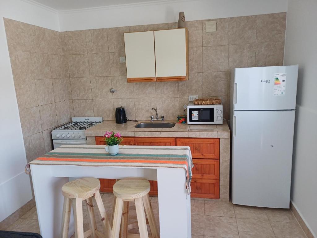 a kitchen with a white refrigerator and two bar stools at Lauquen in Puerto Deseado