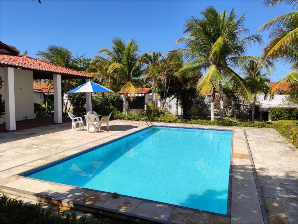 a swimming pool in front of a house with palm trees at Praia Marina Suite - Morro Branco in Beberibe