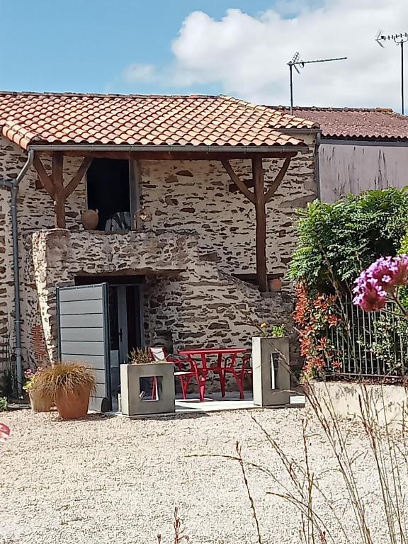 Maison en pierre avec 2 chaises rouges et une table dans l'établissement Fleur de Vigne, à Monnières