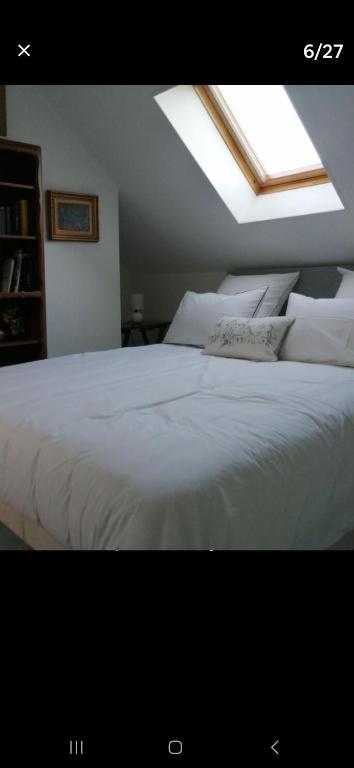 - une chambre avec un grand lit blanc et une lucarne dans l'établissement La p'etit maison rose, à Malouy