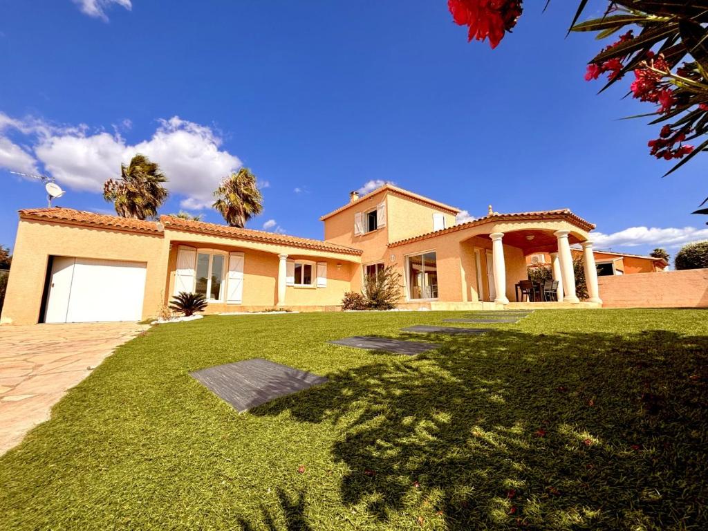 une grande maison avec une pelouse devant dans l'établissement La Villa Harmony, à Portiragnes