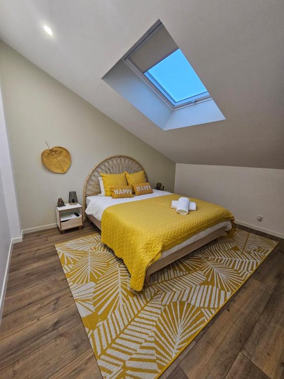 - une chambre avec un lit doté d'une couverture jaune et d'une lucarne dans l'établissement Chambre Isis, à Sainte-Geneviève-des-Bois