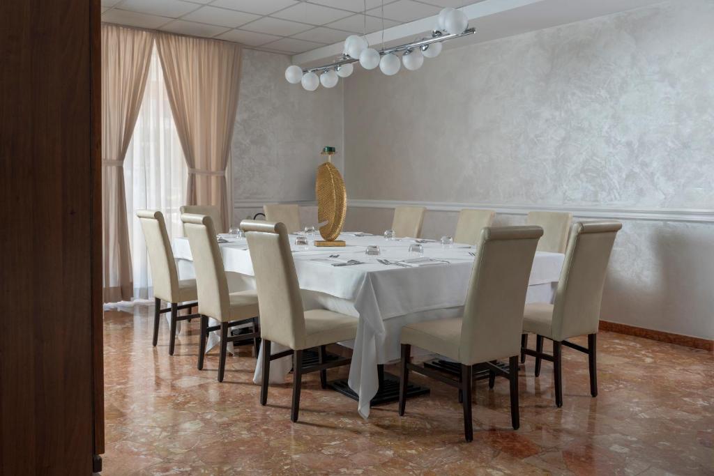 a dining room with a white table and chairs at Hotel Du Soleil in Rimini
