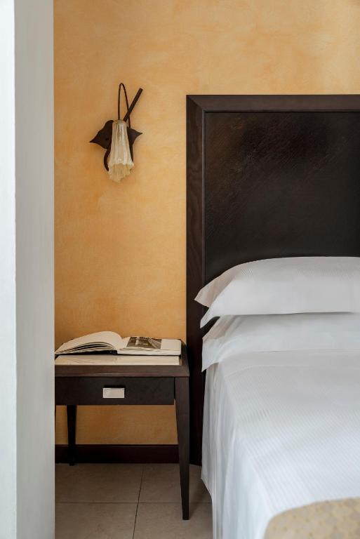a bedroom with a bed and a table with a book at Hotel Du Soleil in Rimini