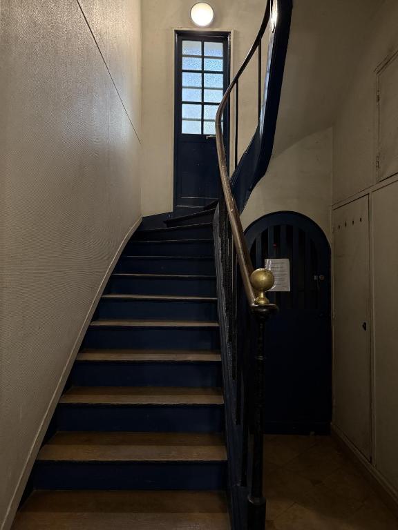 un escalier dans un immeuble avec des escaliers bleus et une fenêtre dans l'établissement Appartement Rive Gauche, à Paris