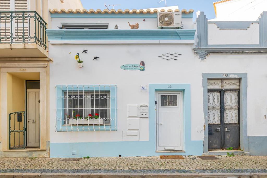 a white house with a blue door and a window at Casinha da Ti Babel in Faro