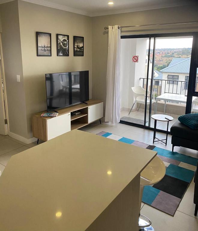 Una sala de estar con un televisor de pantalla plana y un sofá. en The Falls Lifestyle Estate, en Roodepoort