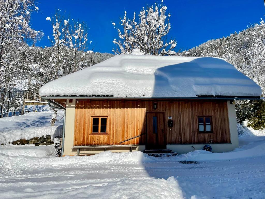 ArriachにあるKlösterle Haus Egonの屋根に雪が積もる小さな木造キャビン