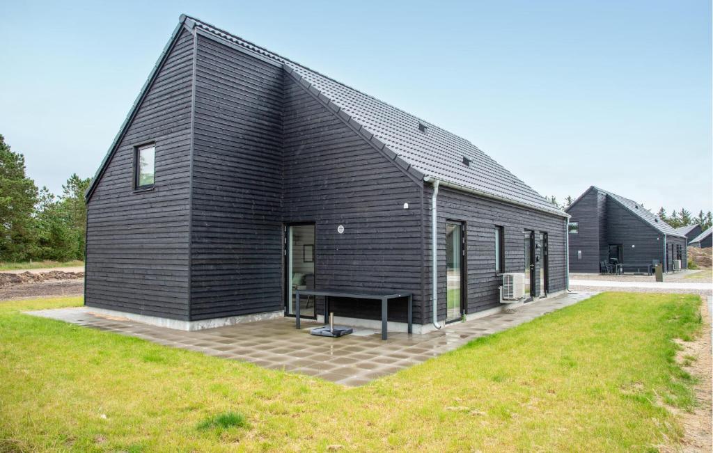 a black house with a bench in front of it at Cozy Home In Rømø With Wifi in Kongsmark
