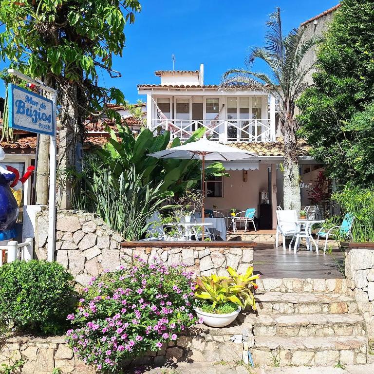 a house with a table and an umbrella and some flowers at Porto Mar de Búzios in Búzios