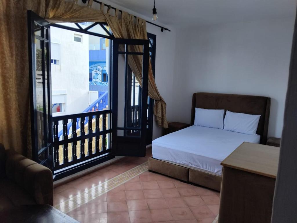 a bedroom with a bed and a large window at Duplex 4 pour les familles in Oualidia