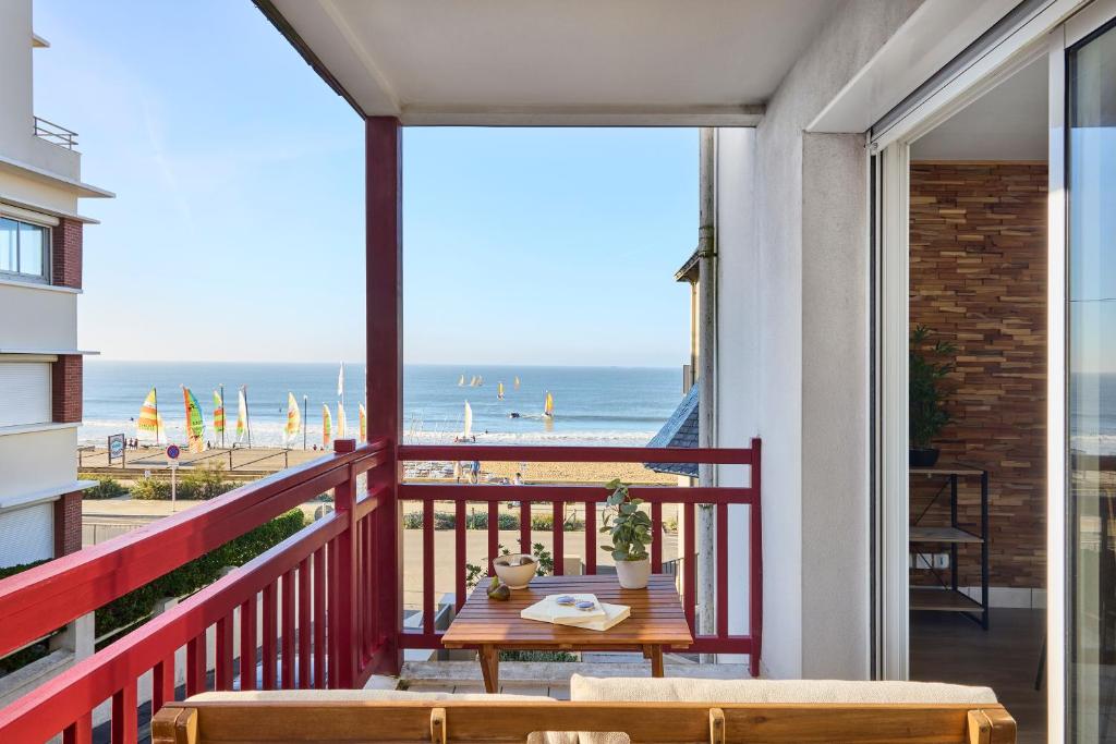 d'un balcon avec une table et une vue sur la plage. dans l'établissement Appartement Les Voiles de Mazy, Rue Calme à Sens Unique, à Pornichet