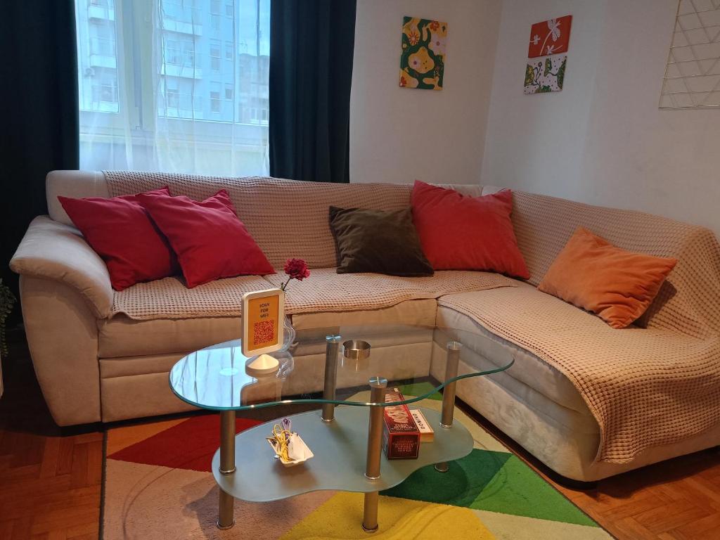 a living room with a couch with pillows and a table at Clockwork orange apartment in Vračar (historical)