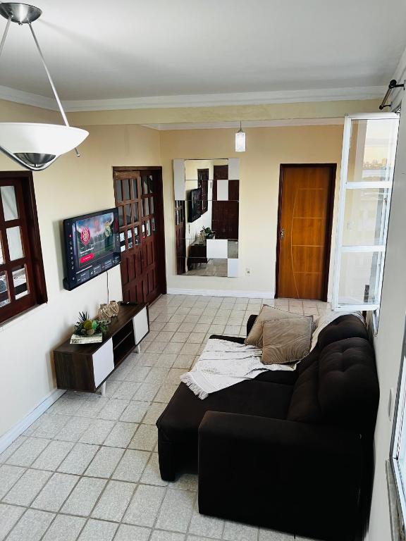 a living room with a couch and a tv at Apto no centro com 3 quartos in Ilhéus