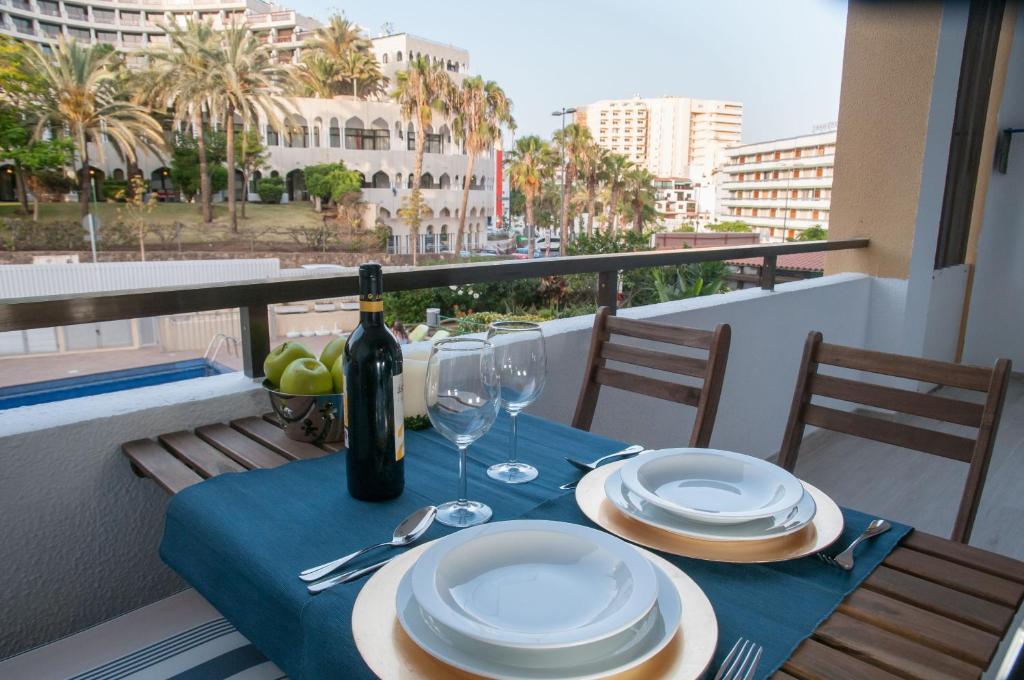 a table with a bottle of wine and glasses on a balcony at Prosurfing Apartamento in Playa del Ingles