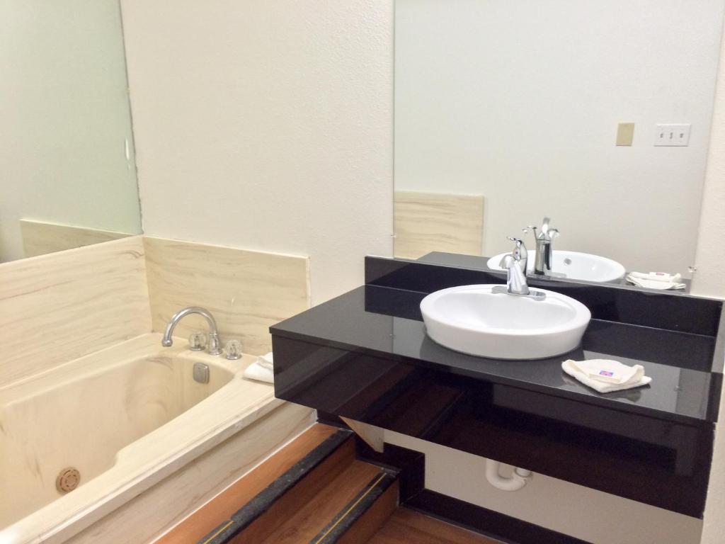 a bathroom with a sink and a tub and a mirror at Motel 6-Longview, TX - North in Longview