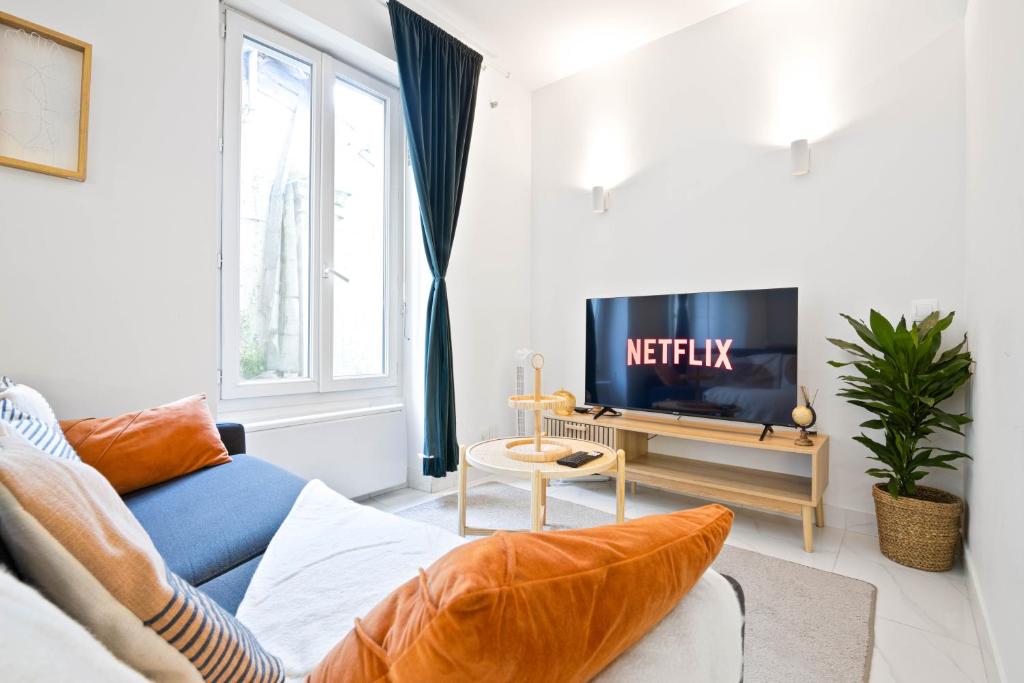 un salon avec un canapé bleu et une télévision dans l'établissement Parisien & Cosy, à Paris