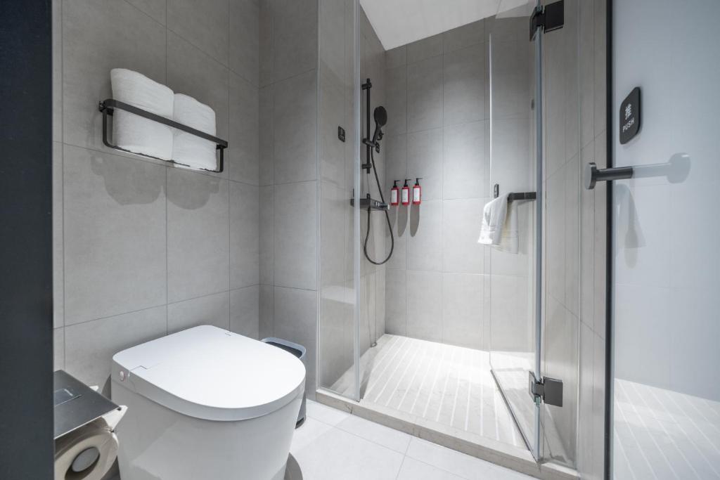 a bathroom with a shower with a toilet and a glass shower door at Atour Light Hotel Chengdu Yulin Street Nijia Bridge in Chengdu