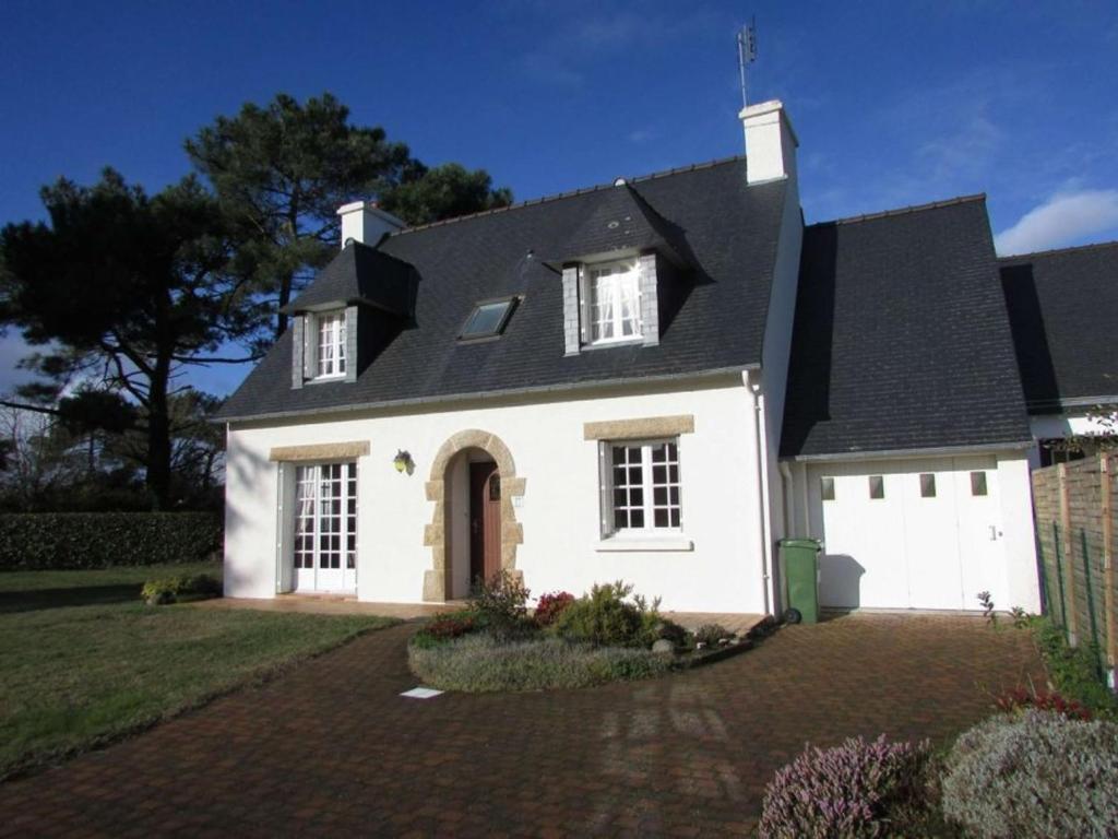 une maison blanche avec un toit noir dans l'établissement Maison 5 pièces calme proche plage avec jardin, animaux acceptés - FR-1-479-186, à Erdeven