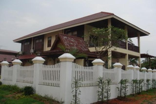 una casa con una cerca blanca delante de ella en Keerawan House Rim Khong, en Ban Wat Luang