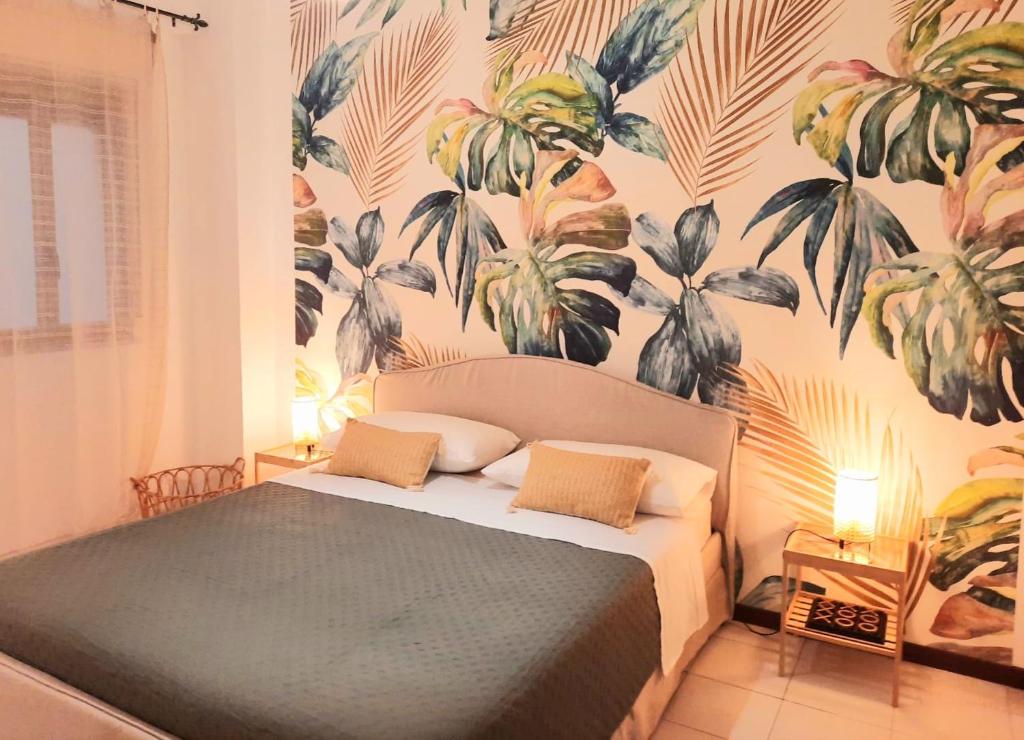 a bedroom with a bed with a tropical wallpaper at Arcadia Golden Bay in Giardini Naxos