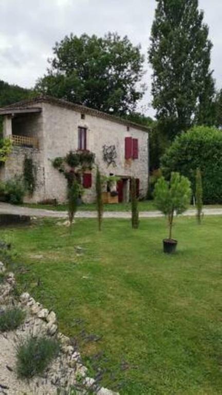 une vieille maison dans une cour avec des arbres devant elle dans l'établissement La bordette, à Sauveterre