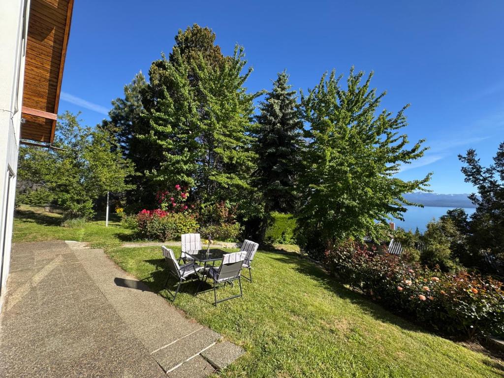 a bench sitting on the grass with a view of the water at Casa con parque y vista al lago in San Carlos de Bariloche