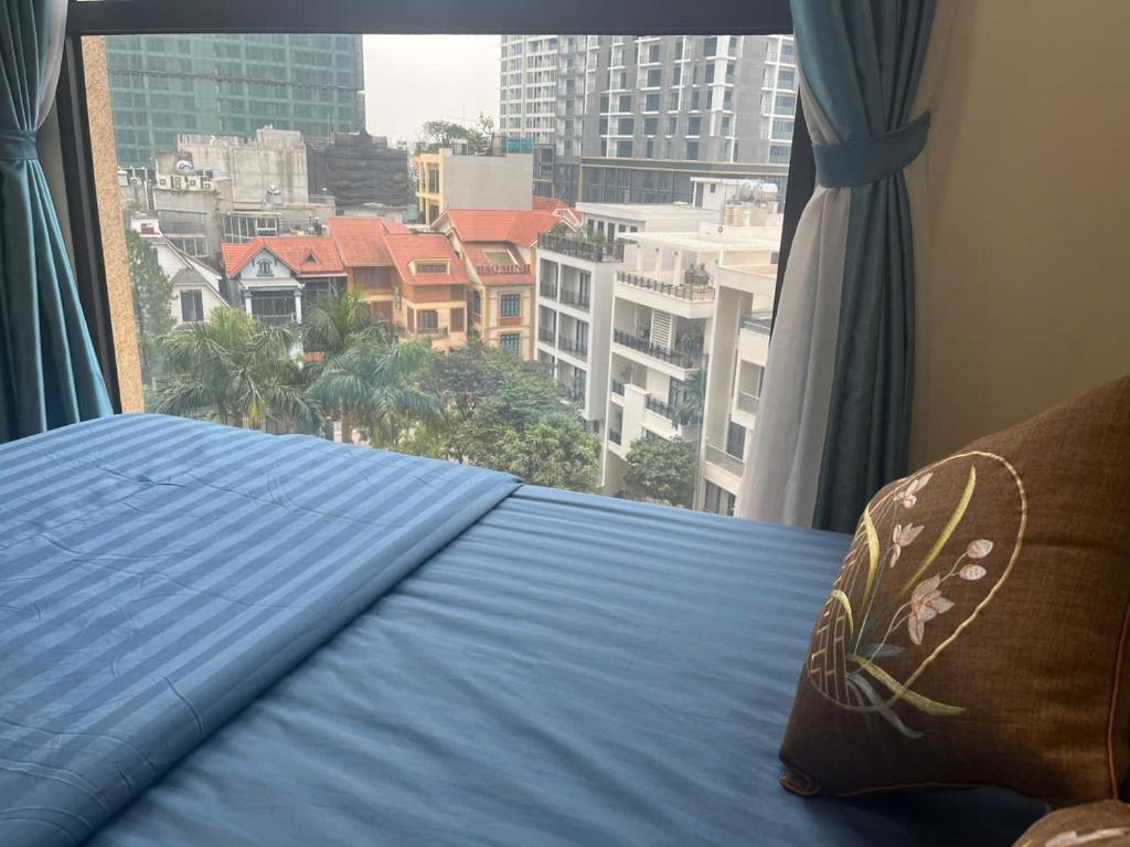 a bed in a room with a view of a city at HT Home D'el, Dorado 3 in Hanoi