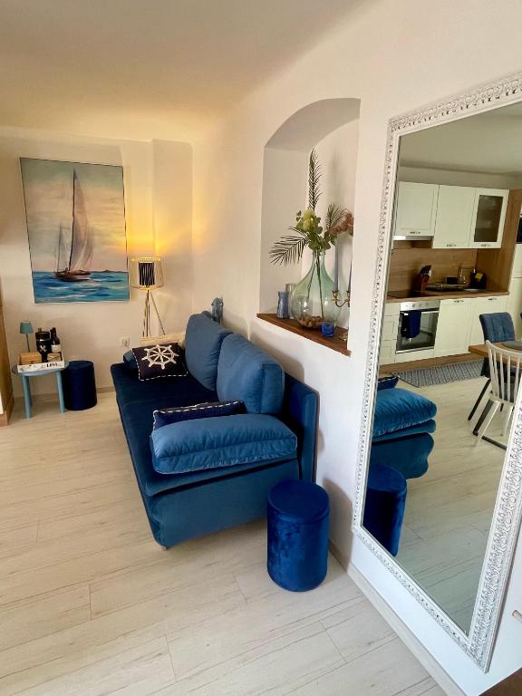 a living room with a blue couch and a mirror at Holiday House Baska Hill in Jurandvor