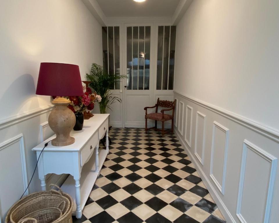 un couloir avec une table et une lampe sur un sol en damier dans l'établissement Maison au cœur des vignes, à Saint-Estèphe