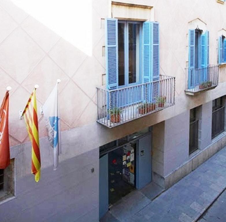 un edificio con dos banderas a un lado en Alberg Girona Xanascat, en Girona