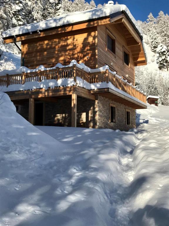 une cabane en rondins avec une terrasse dans la neige dans l'établissement chalet Marigo, Pra-loup 1500, à Uvernet