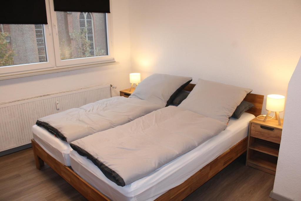 Una cama en una habitación con dos mesitas de noche y dos lámparas. en FeWo Oberhausen-Styrum, en Oberhausen