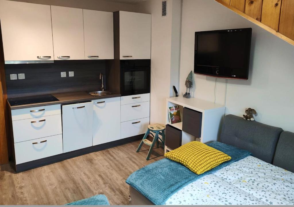 una cucina con armadietti bianchi e una TV in camera di Apartment Misty Forest a Kranjska Gora